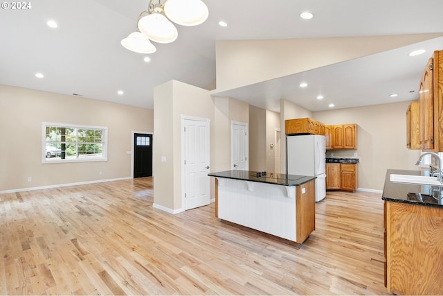 kitchen featuring sink, a kitchen breakfast bar, white refrigerator, a kitchen island, and light wood-type flooring