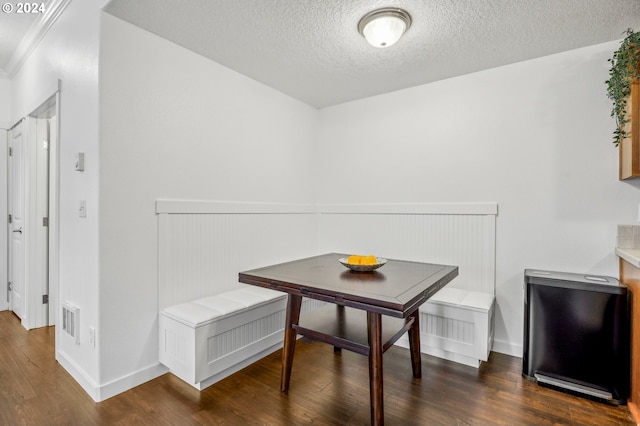 dining room featuring dark hardwood / wood-style flooring, breakfast area, a textured ceiling, and ornamental molding