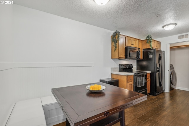 kitchen featuring black appliances, dark hardwood / wood-style flooring, a textured ceiling, and washer / clothes dryer