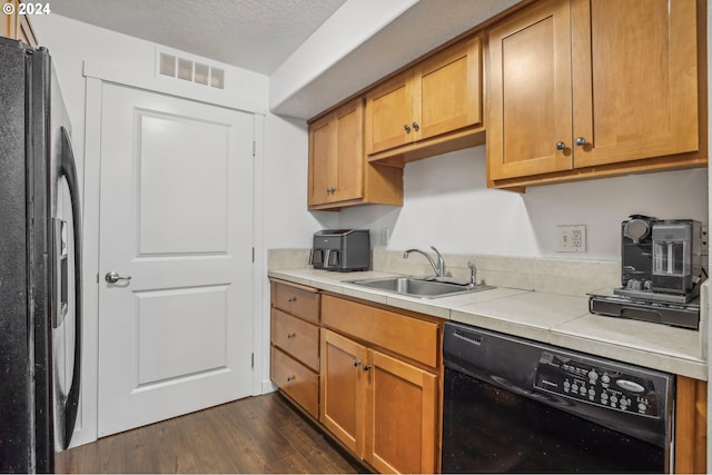 kitchen featuring a textured ceiling, sink, dark hardwood / wood-style floors, and black appliances