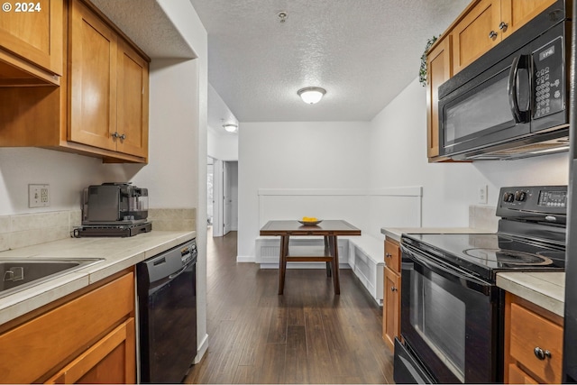 kitchen with dark hardwood / wood-style flooring, black appliances, a textured ceiling, and sink