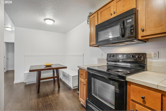 kitchen featuring black appliances, dark hardwood / wood-style flooring, and a textured ceiling