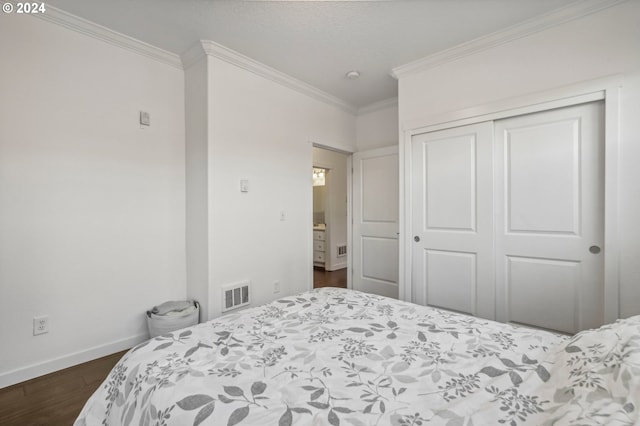 bedroom featuring dark hardwood / wood-style floors, crown molding, and a closet