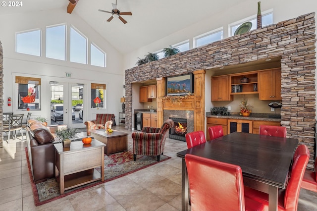 tiled living room featuring french doors, ceiling fan, high vaulted ceiling, a premium fireplace, and beamed ceiling