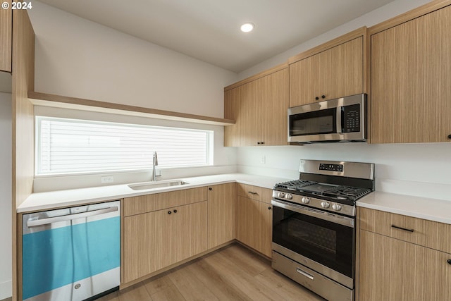 kitchen featuring light brown cabinetry, light wood-type flooring, stainless steel appliances, and sink