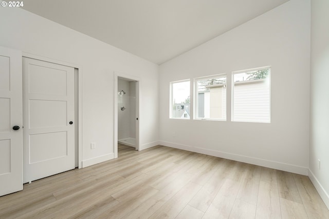 unfurnished bedroom featuring vaulted ceiling, a closet, and light hardwood / wood-style flooring