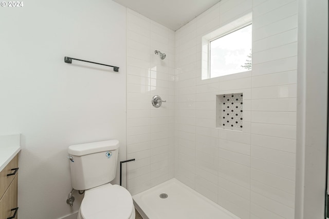 bathroom featuring a tile shower, vanity, and toilet