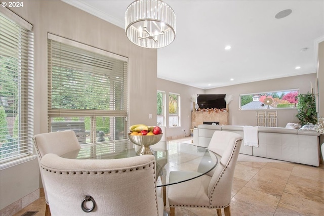 dining area with plenty of natural light, an inviting chandelier, crown molding, and a tiled fireplace