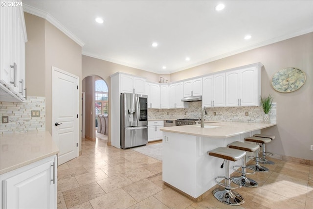 kitchen with a breakfast bar, stainless steel refrigerator with ice dispenser, ornamental molding, white cabinetry, and kitchen peninsula