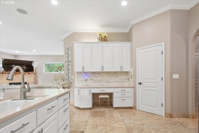 kitchen featuring backsplash, white cabinetry, crown molding, and sink