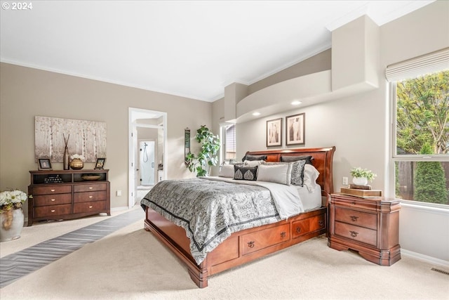 bedroom with ensuite bath, light colored carpet, and multiple windows