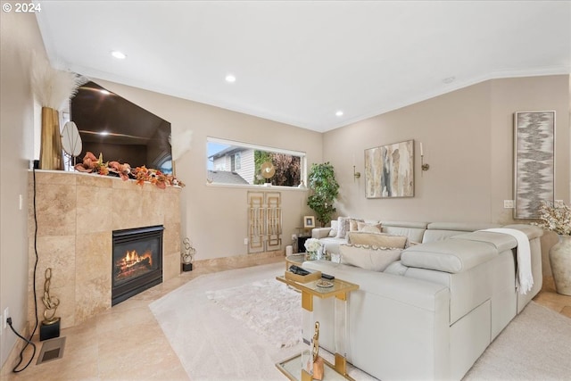 living room featuring a tile fireplace, light tile patterned floors, and ornamental molding