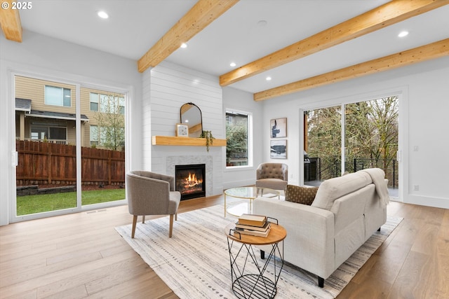 living room with light hardwood / wood-style flooring, beam ceiling, and a fireplace