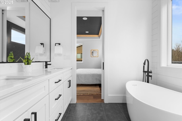 bathroom featuring vanity, a washtub, and tile patterned floors