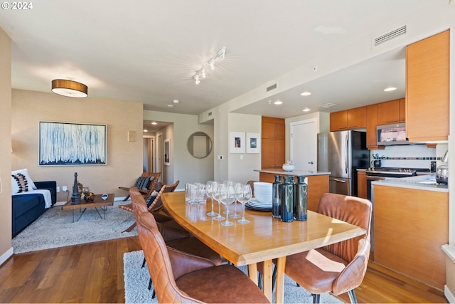 dining area featuring track lighting and hardwood / wood-style flooring