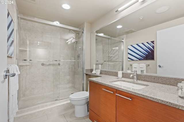 bathroom featuring tile patterned floors, vanity, a shower with shower door, and toilet