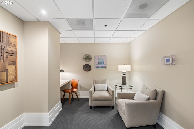 living area featuring dark colored carpet and a drop ceiling