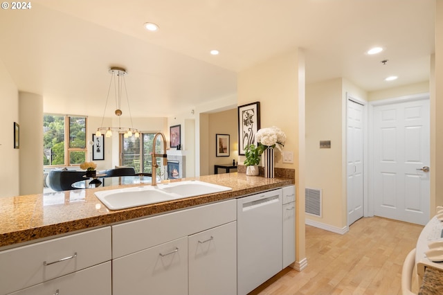 kitchen featuring light hardwood / wood-style flooring, white dishwasher, dark stone countertops, sink, and pendant lighting