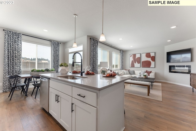 kitchen with stainless steel dishwasher, dark wood-type flooring, sink, pendant lighting, and white cabinets