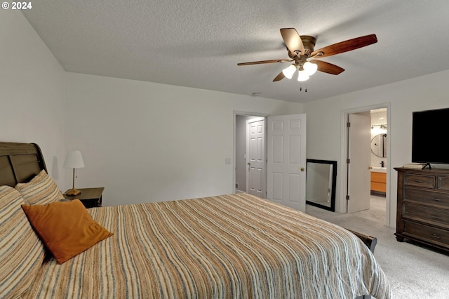 bedroom featuring ensuite bath, light carpet, a textured ceiling, and ceiling fan