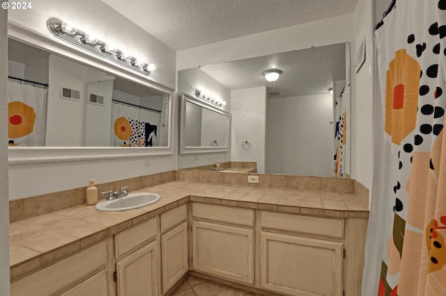 bathroom with vanity, a textured ceiling, a shower with shower curtain, and tile patterned flooring