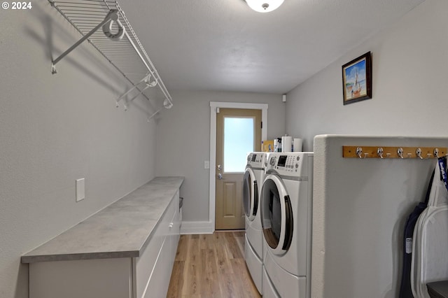 clothes washing area featuring light hardwood / wood-style flooring, separate washer and dryer, and cabinets