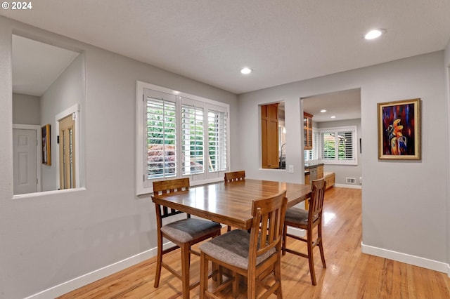 dining room featuring light hardwood / wood-style flooring, a textured ceiling, and a wealth of natural light