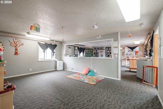 playroom featuring dark carpet and a textured ceiling