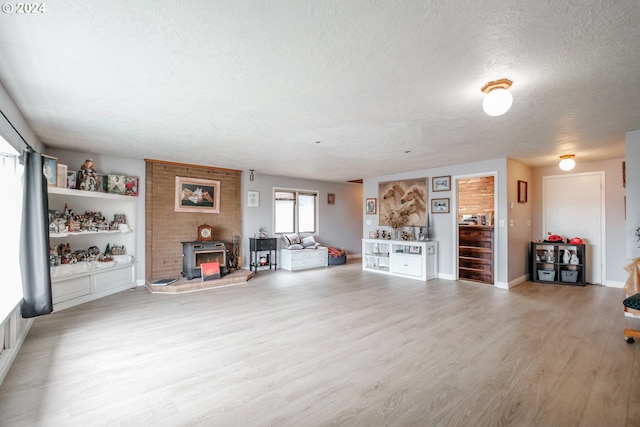 unfurnished living room featuring a wood stove, a textured ceiling, and light wood-type flooring