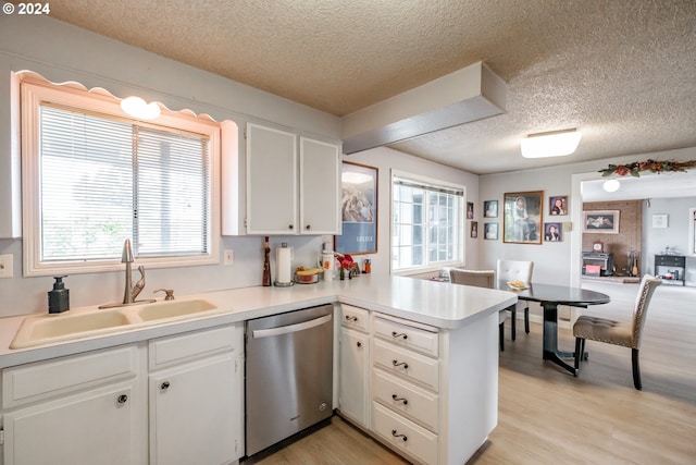 kitchen with kitchen peninsula, white cabinetry, light wood-type flooring, dishwasher, and sink