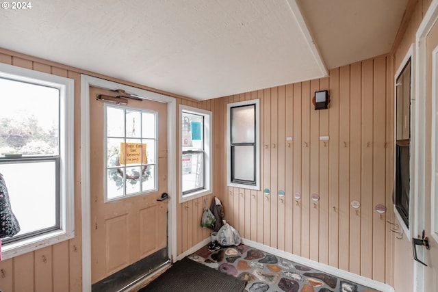 doorway featuring wooden walls and a textured ceiling