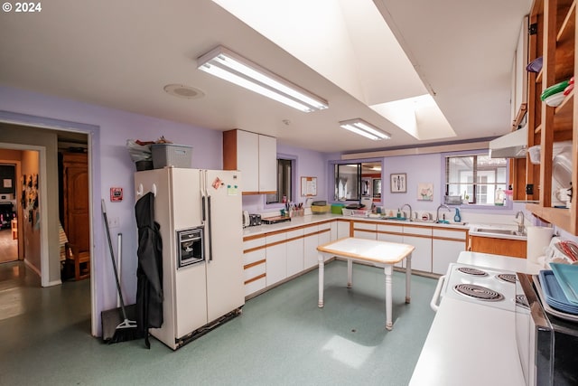 kitchen with white cabinetry, white refrigerator with ice dispenser, and kitchen peninsula