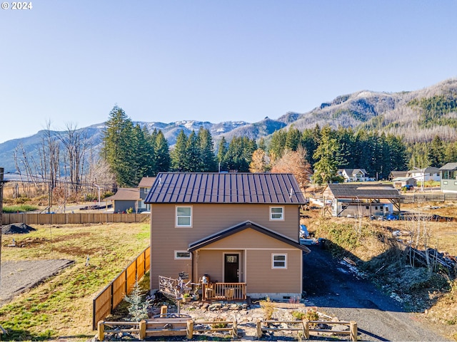 rear view of house featuring fence, a mountain view, and metal roof