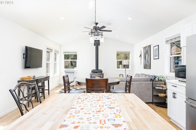 interior space featuring light wood finished floors, a ceiling fan, lofted ceiling, a wood stove, and recessed lighting