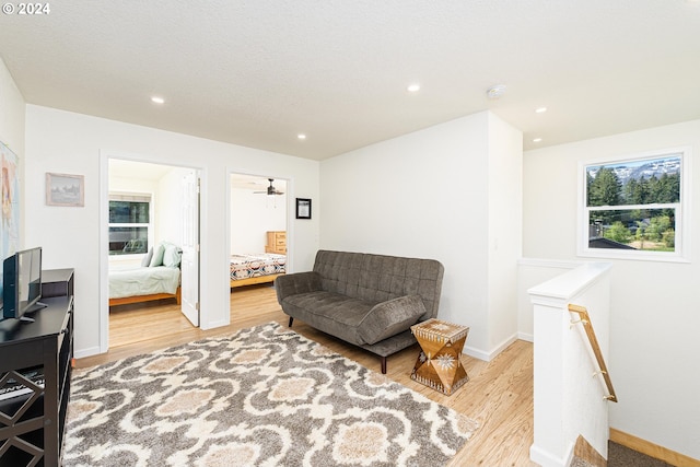 sitting room featuring baseboards, light wood finished floors, an upstairs landing, and recessed lighting