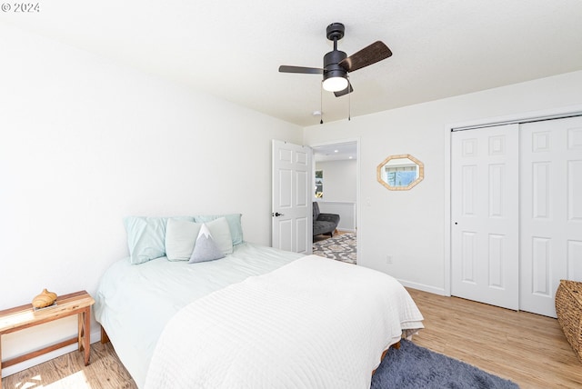 bedroom with light wood-style floors, ceiling fan, baseboards, and a closet