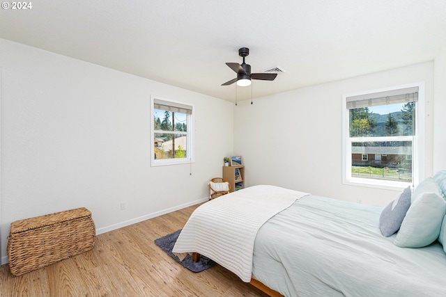 bedroom with multiple windows, wood finished floors, a ceiling fan, and baseboards