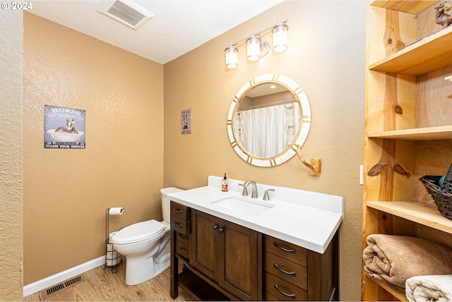 full bathroom with toilet, vanity, wood finished floors, and visible vents