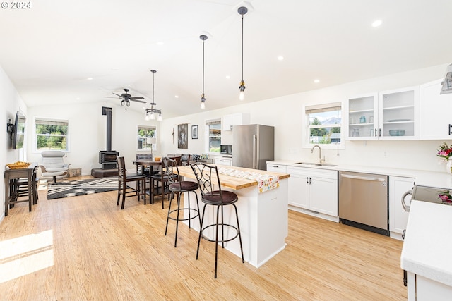 kitchen featuring open floor plan, stainless steel appliances, a sink, and glass insert cabinets