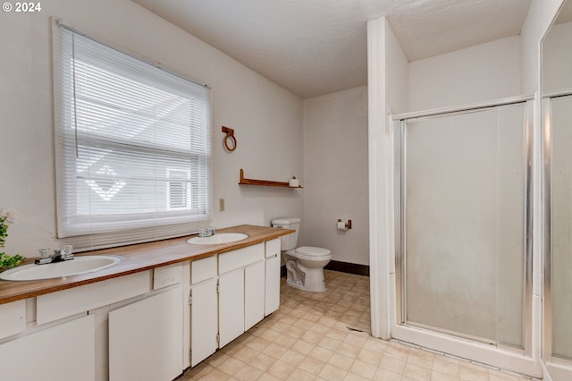 bathroom with a textured ceiling, vanity, toilet, and walk in shower