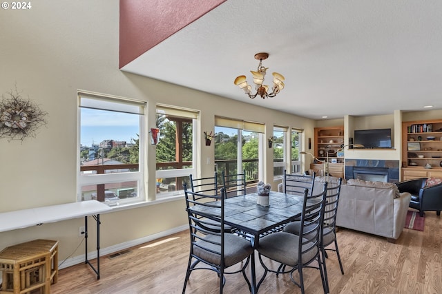 dining area featuring a notable chandelier, light hardwood / wood-style floors, and a tiled fireplace