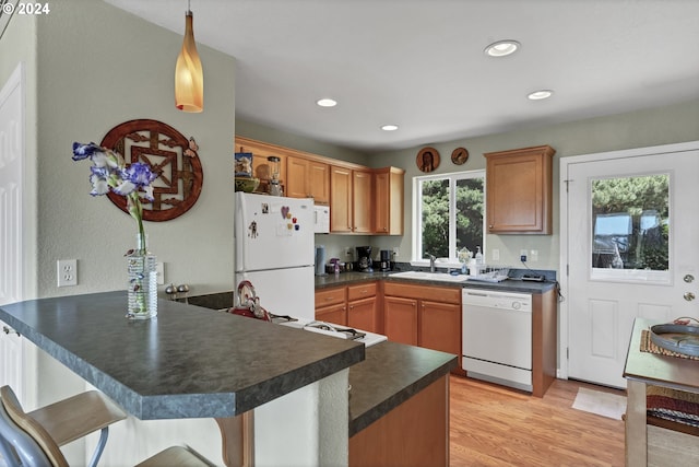 kitchen featuring kitchen peninsula, sink, pendant lighting, and white appliances