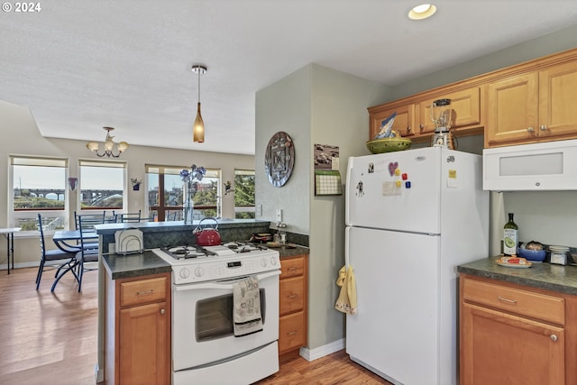 kitchen featuring white appliances, decorative light fixtures, light hardwood / wood-style flooring, a notable chandelier, and kitchen peninsula