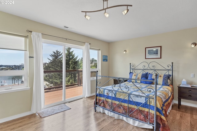 bedroom with access to outside and hardwood / wood-style flooring