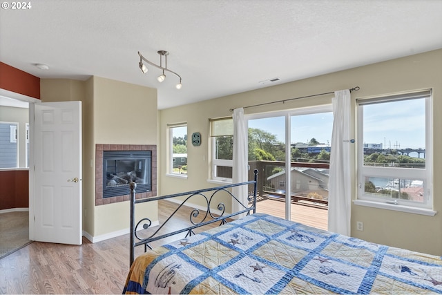 unfurnished bedroom with access to outside, multiple windows, light hardwood / wood-style floors, and a textured ceiling