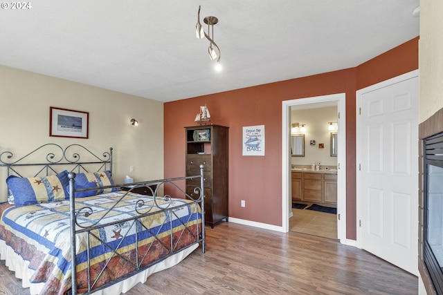 bedroom with wood-type flooring, ensuite bath, and sink