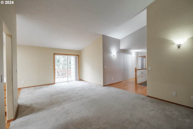 carpeted empty room with vaulted ceiling