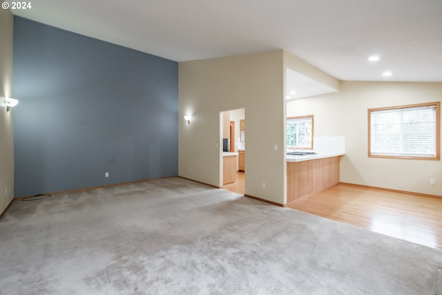 carpeted spare room with a wealth of natural light and vaulted ceiling