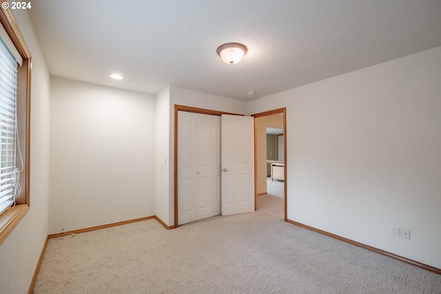 unfurnished bedroom with a closet, light carpet, and a textured ceiling