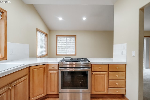 kitchen with tile countertops, gas stove, vaulted ceiling, and light hardwood / wood-style floors